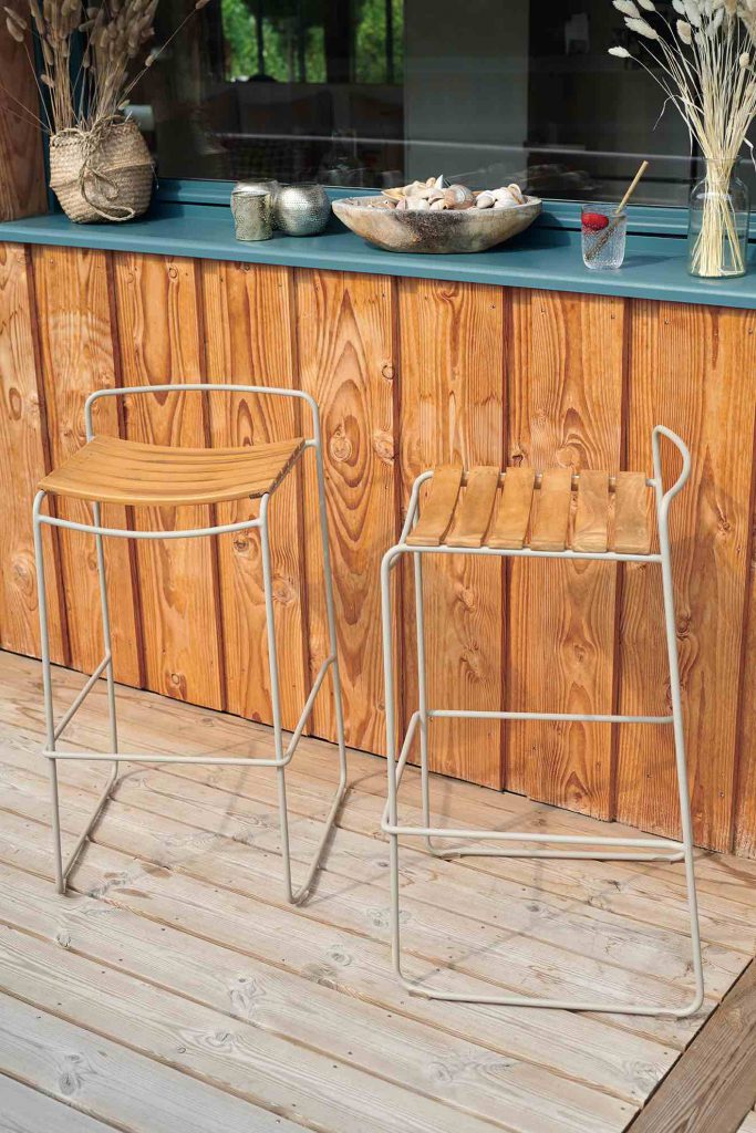 Deux tabourets en bois sur une terrasse en bois.