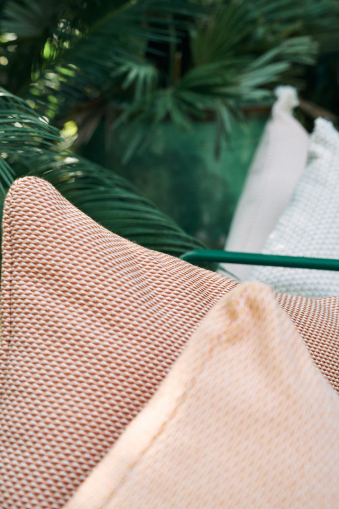 Un groupe d’oreillers posés sur un banc à côté d’un palmier.