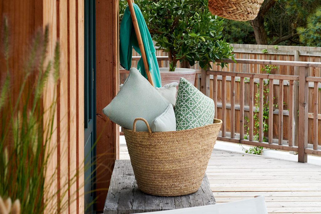 Un panier en osier sur une terrasse en bois.