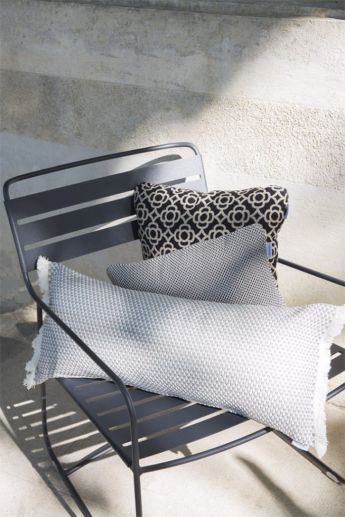 Une chaise en métal noir avec des oreillers.
