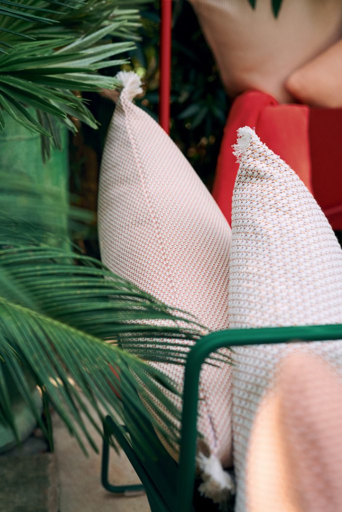 Une chaise avec des oreillers et un palmier en arrière-plan.