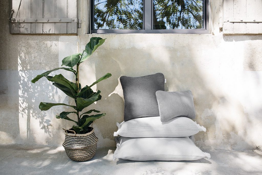 Une paire d'oreillers et une plante en pot devant une fenêtre.