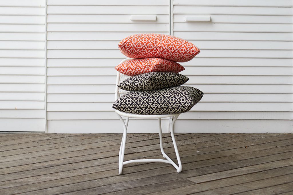 Une pile d'oreillers sur une chaise blanche.