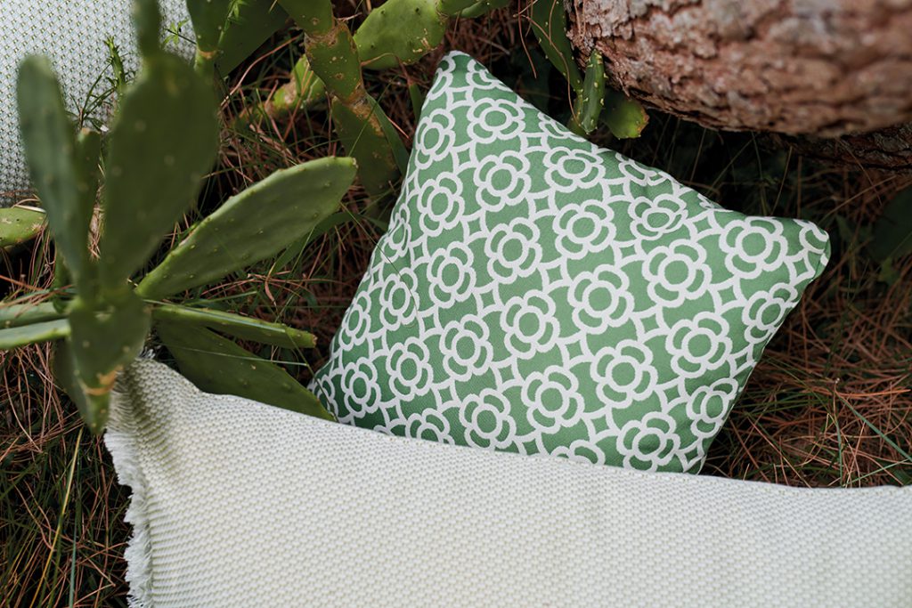 Un oreiller vert et blanc avec des cactus dans l'herbe.