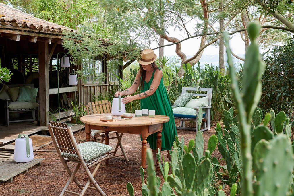 Une femme vêtue d'une robe verte assise à une table près de plantes de cactus.