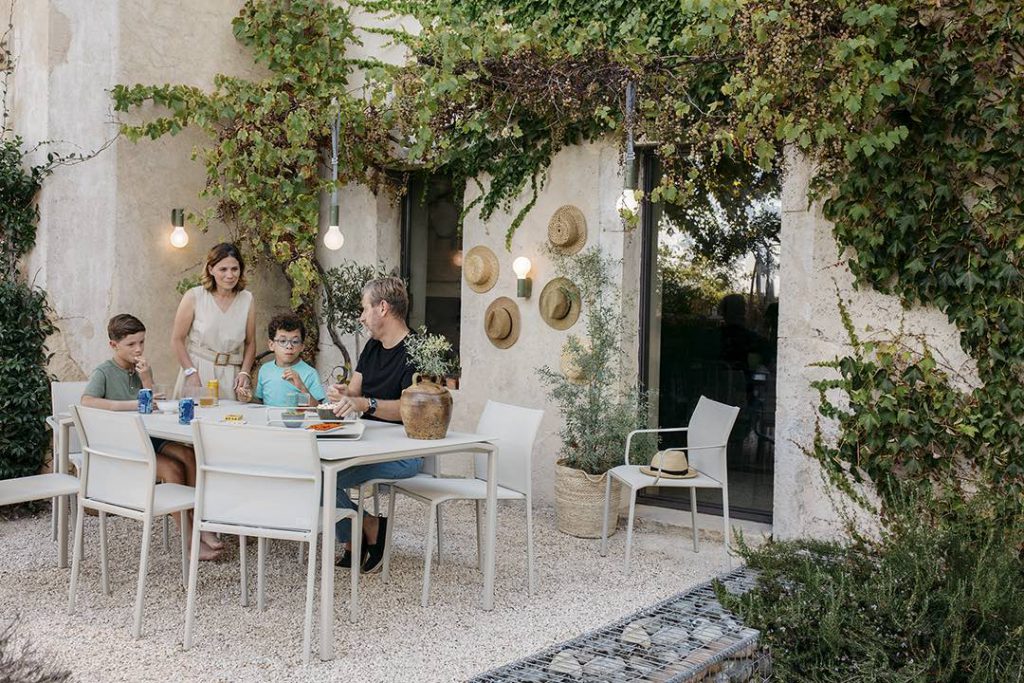 Une famille est assise autour d’une table dans un jardin.