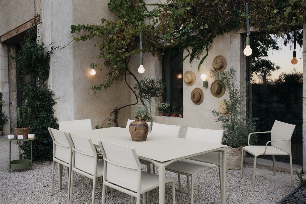 Une table à manger et des chaises blanches dans un cadre extérieur.