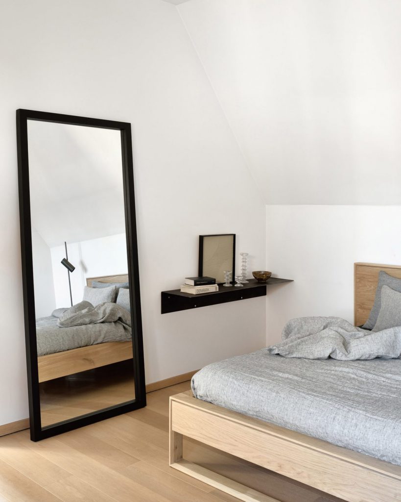 Une chambre avec un lit, une commode et un miroir.