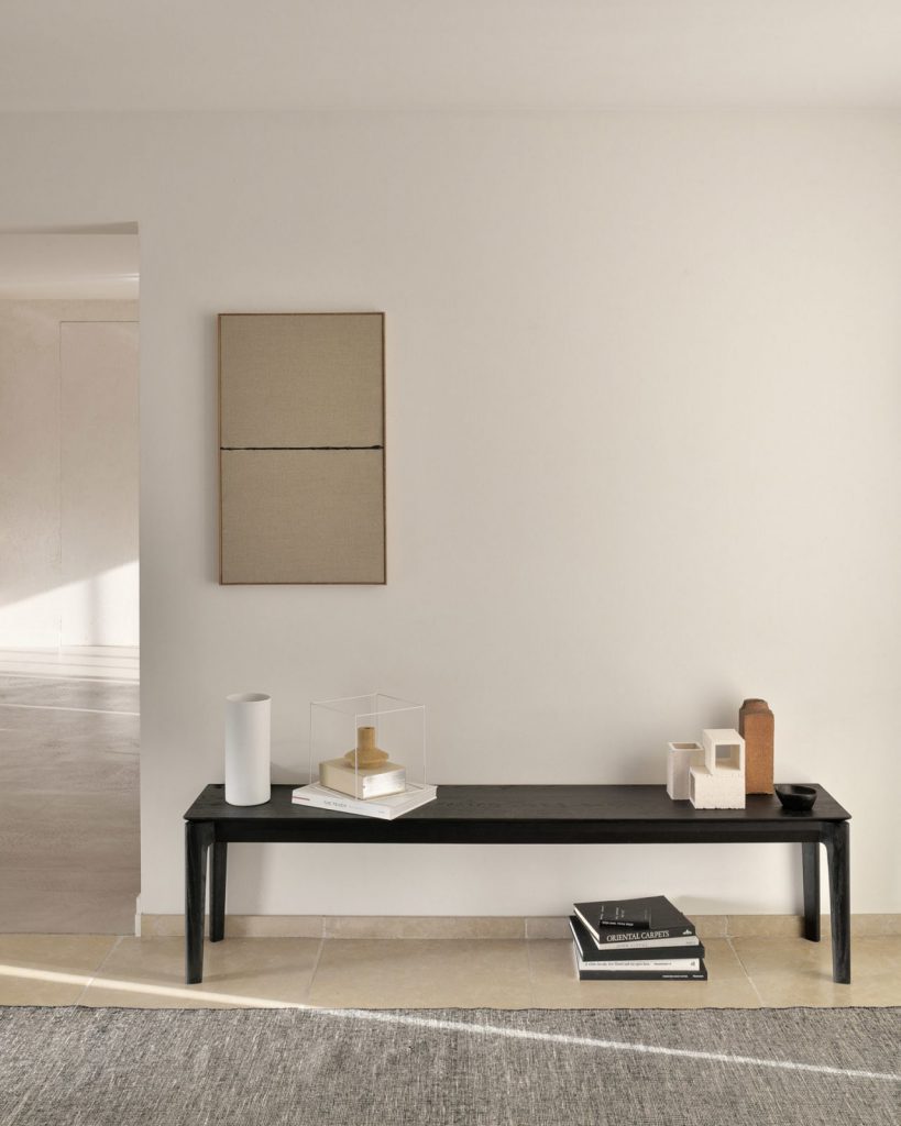 Un banc noir dans une pièce aux murs blancs.