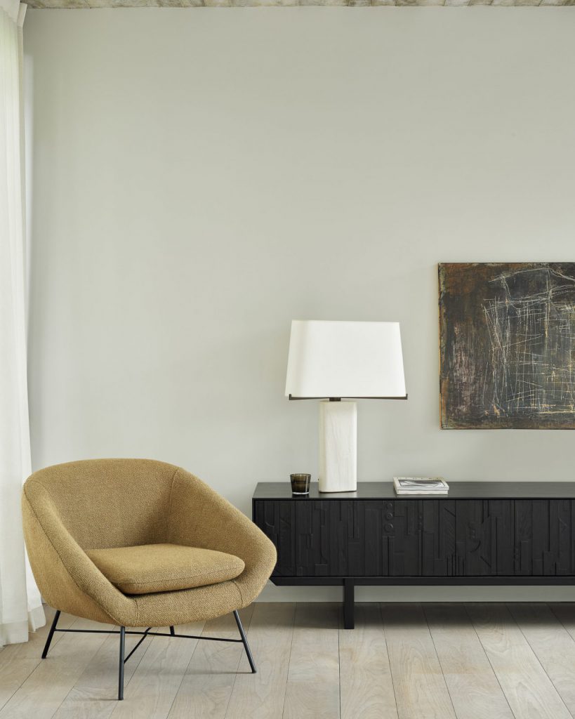 Un salon avec une chaise et un tableau au mur.