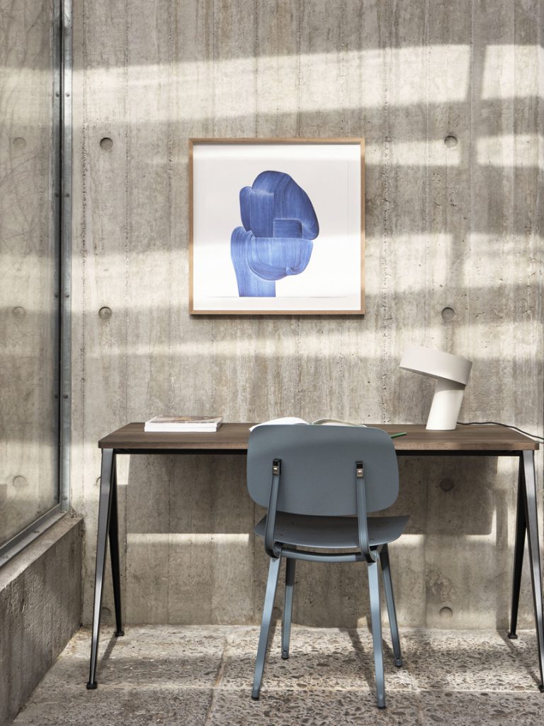 Un bureau avec une chaise et un tableau bleu au mur.