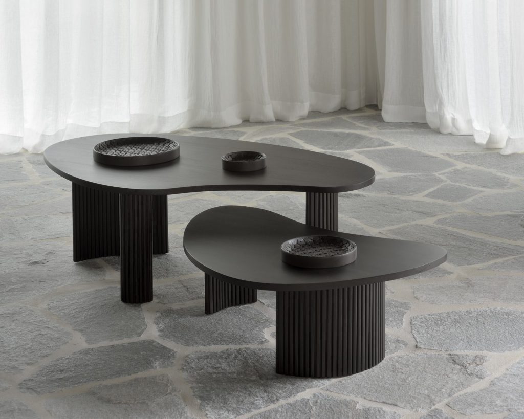 Deux tables basses noires sur un sol en pierre.