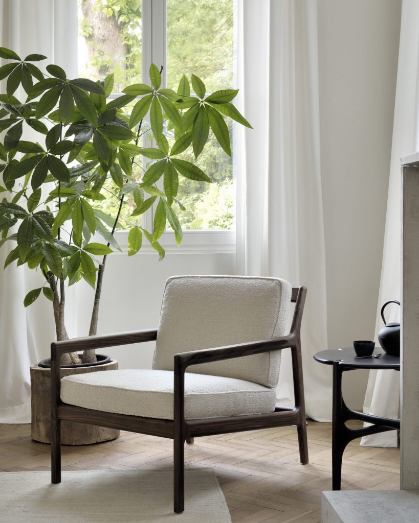 Une chaise blanche avec une plante en pot devant une fenêtre.