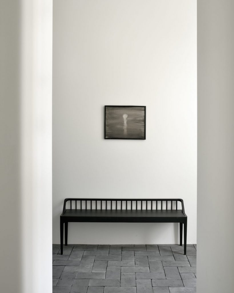 Un banc noir dans une pièce avec un tableau au mur.