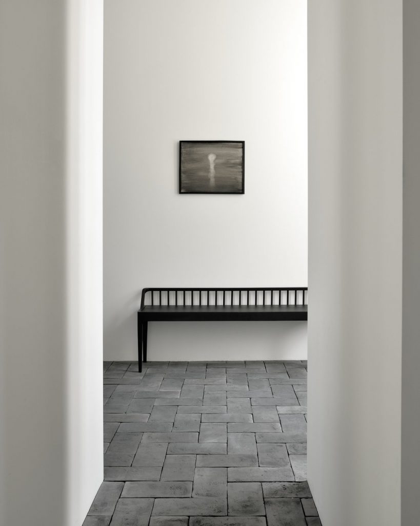 Une pièce vide avec un banc et un tableau au mur.