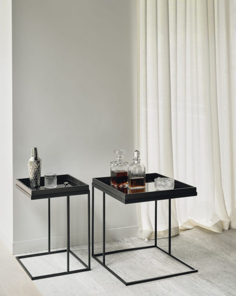 Deux tables d'appoint noires dans une pièce avec un rideau.