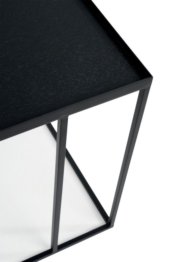 Une table basse en métal noir avec un plateau en verre.
