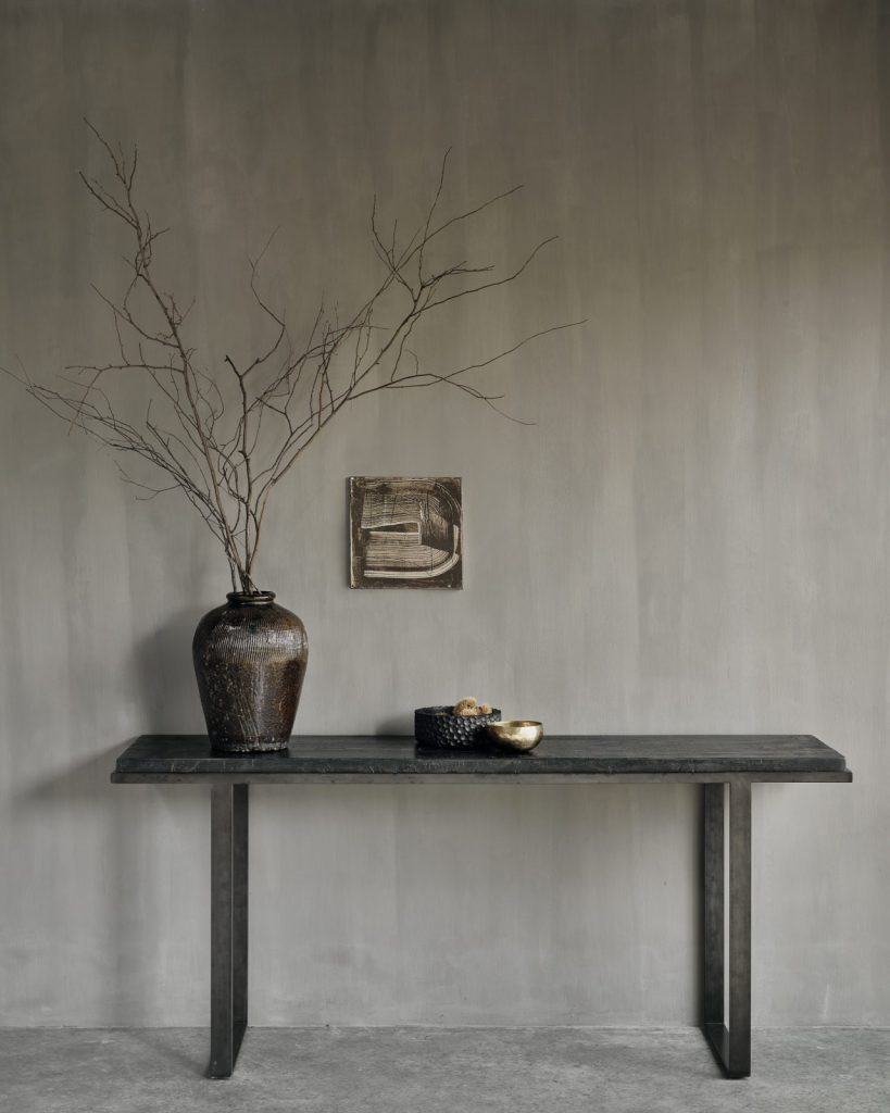 Une console noire avec un vase sur le dessus.
