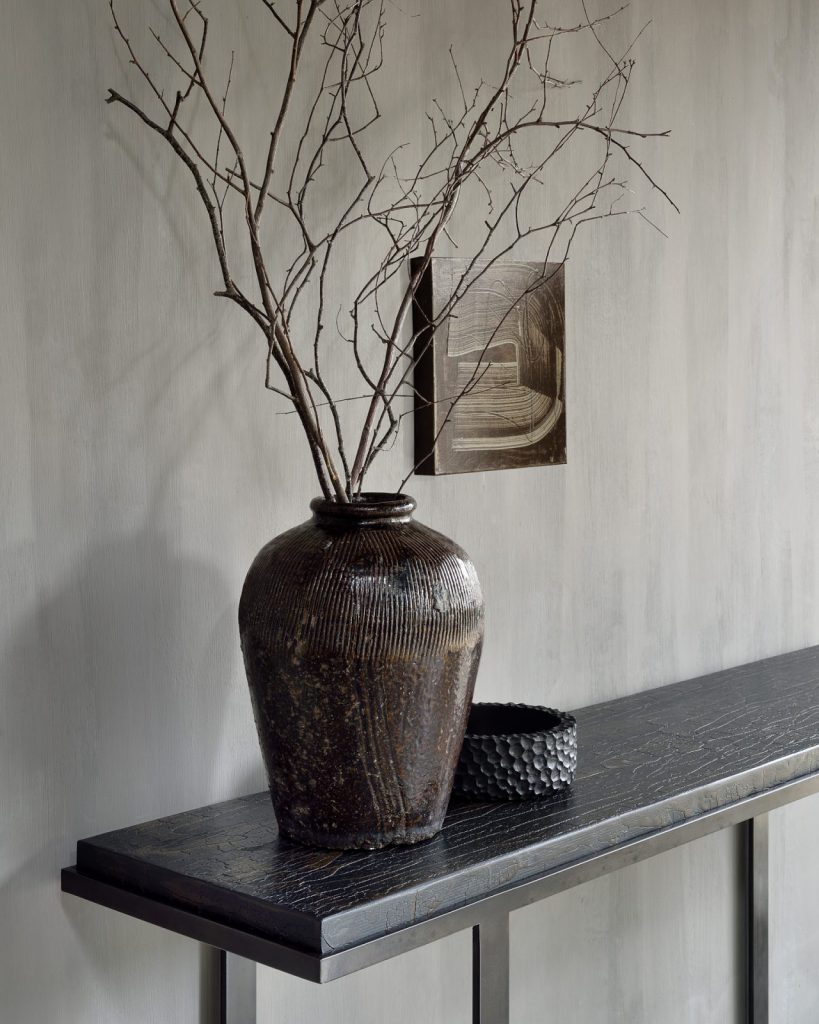 Un vase avec une branche dessus est posé sur une table.