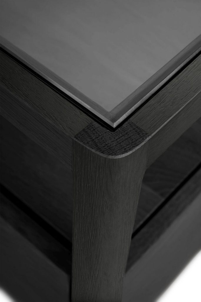 Une table basse noire avec un plateau en verre.
