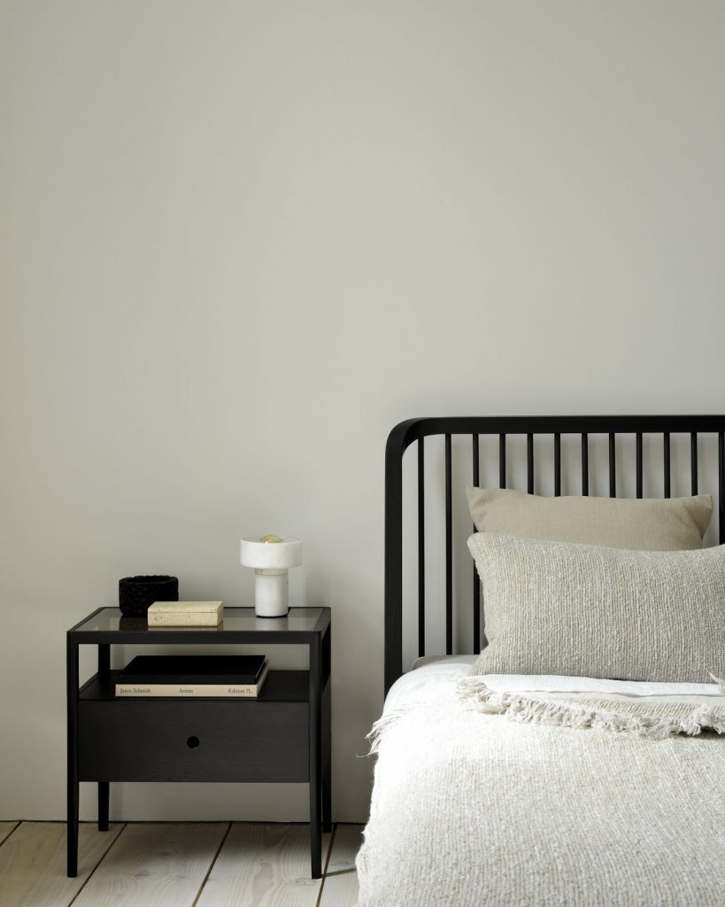 Un lit avec une table de nuit à côté, dotée d'un tiroir coulissant.