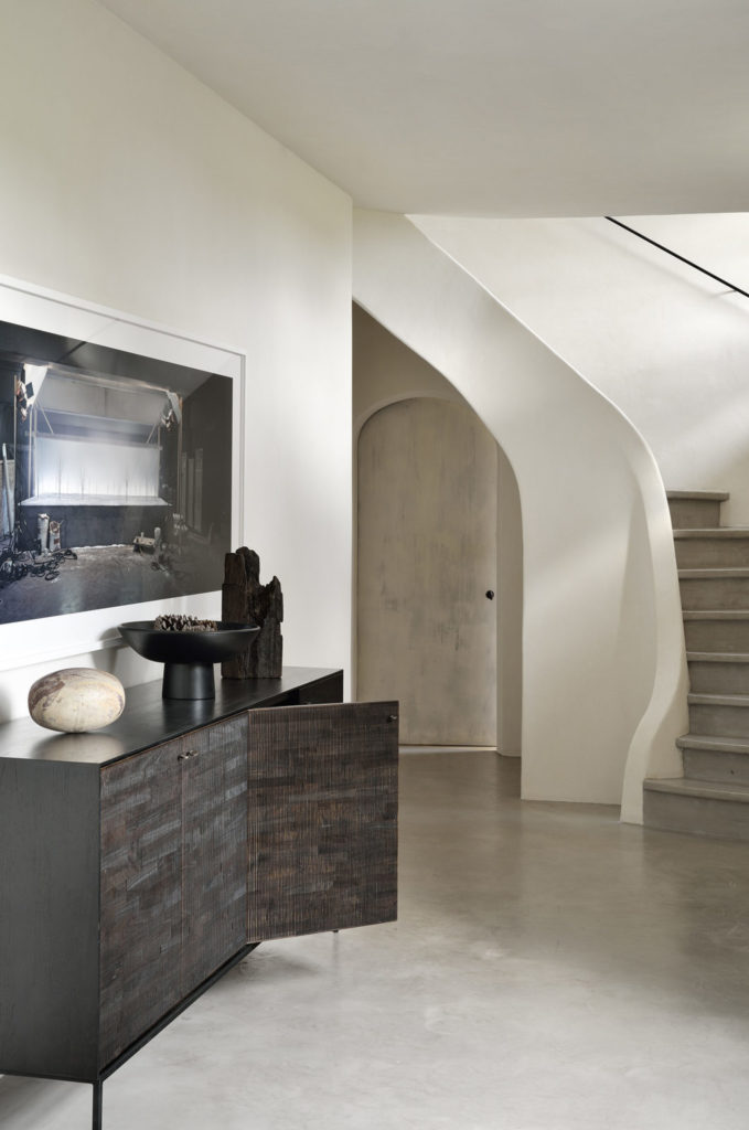 Buffet ethnicraft grooves en teck teinté foncé dans une maison avec escalier et cadre au mur