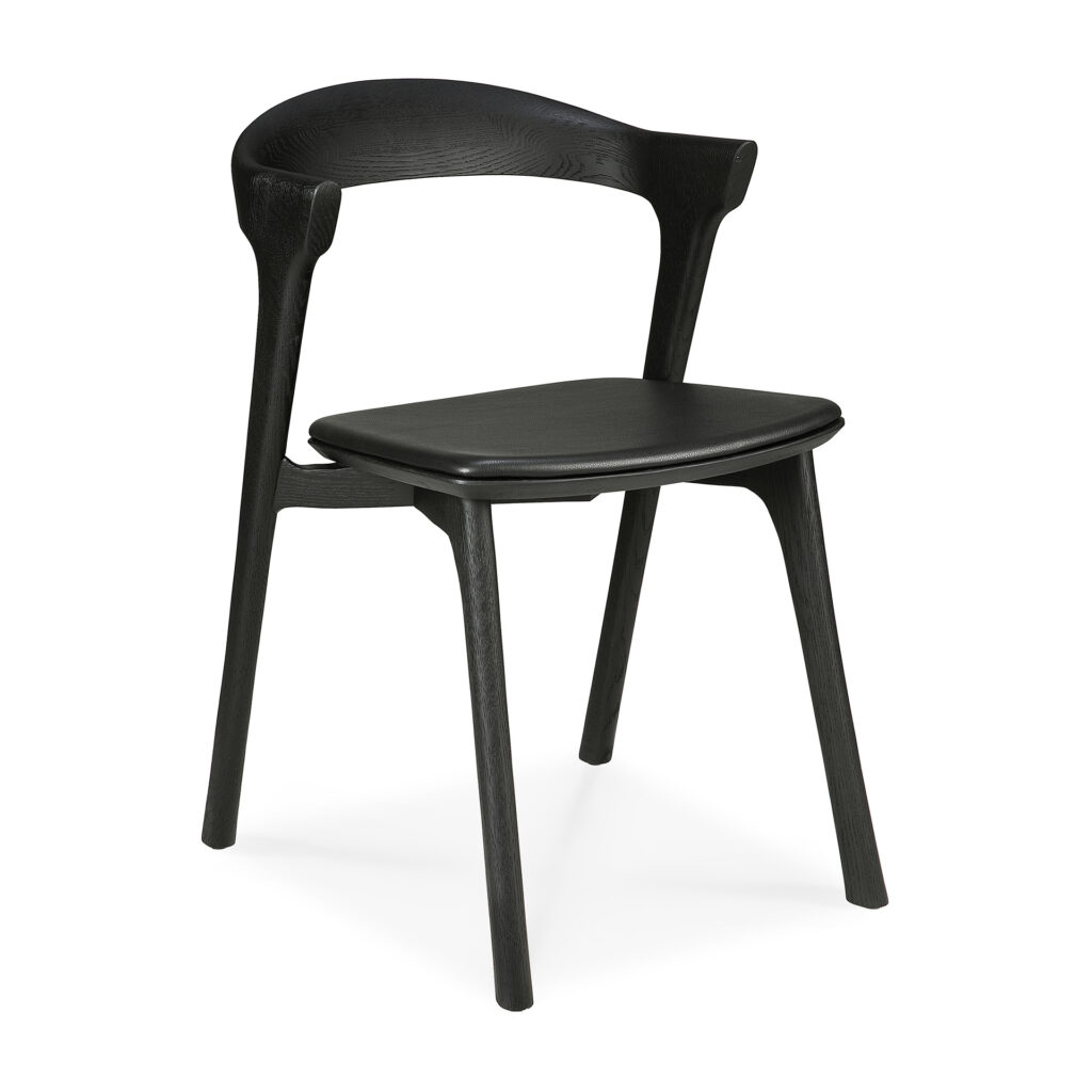 La Chaise Bok en chêne noir, assise en cuir est une chaise en bois noir de style moderne avec un dossier incurvé et quatre pieds qui présente un élégant siège en cuir.