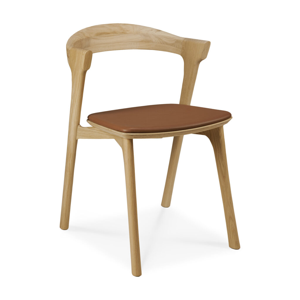 La Chaise Bok en chêne présente une structure en bois avec un dossier incurvé et est complétée par un coussin d'assise marron clair recouvert de luxueux cuir Cognac.