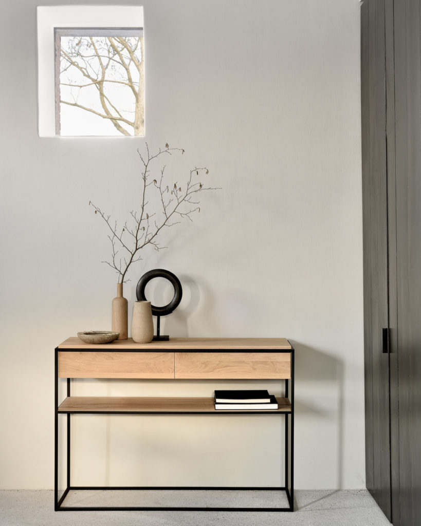 Une console Monolit en chêne en bois de chêne placée dans une pièce avec une fenêtre.