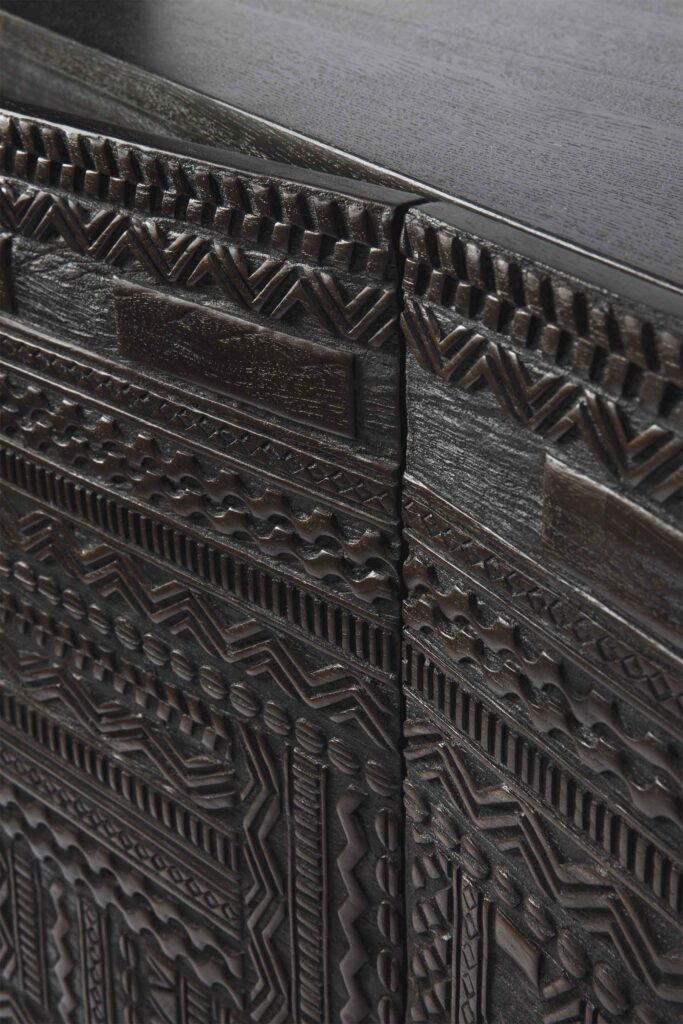 Gros plan d'une surface en bois foncé avec des sculptures géométriques complexes dans un motif répétitif, parfait pour le Buffet Tabwa en teck noir 3 portes.