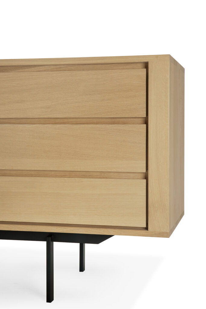 Le Buffet Shadow, réalisé en chêne avec trois portes et trois tiroirs, respire l'élégance moderne avec son design en bois et ses pieds en métal noir.