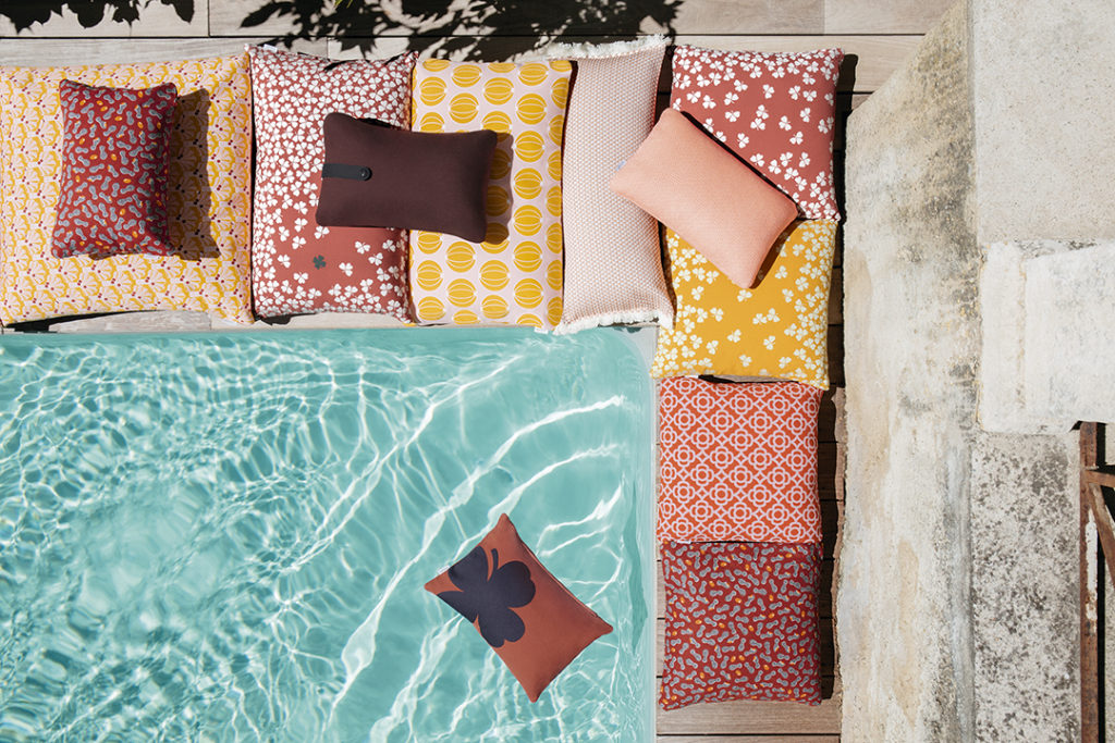 Un groupe de Coussin Lorette 44x44cm posé à côté d'une piscine.