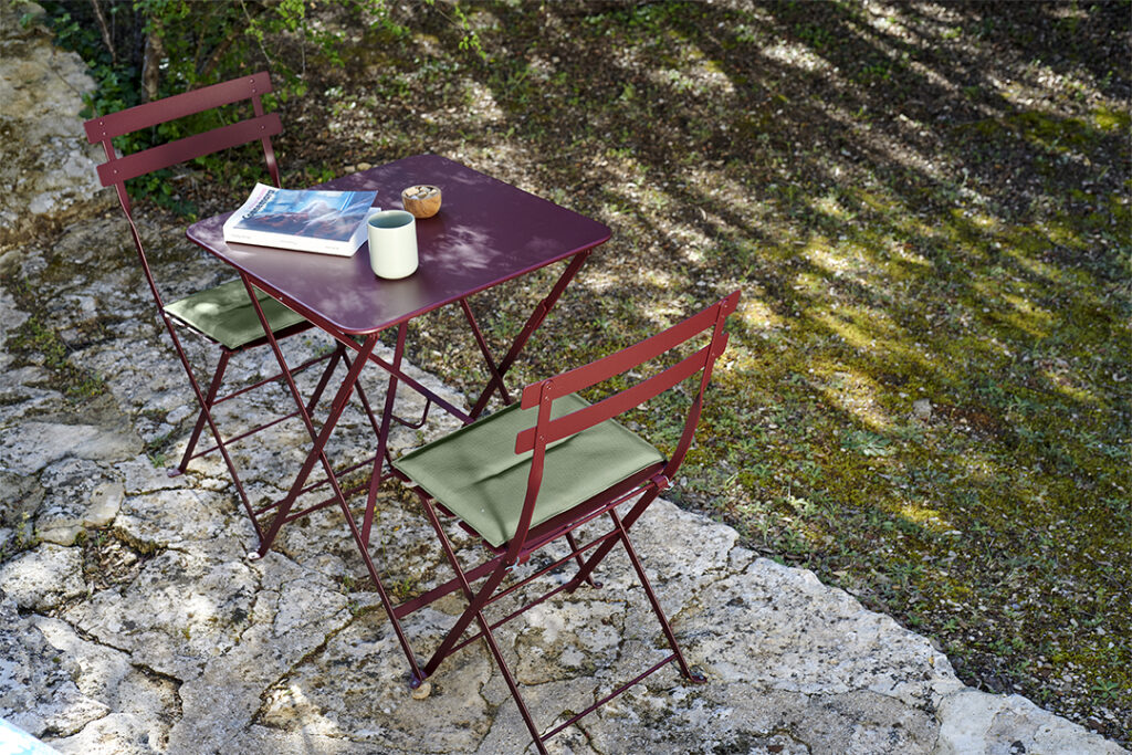 Une Table carrée Bistro, 57 x 57 cm, avec deux chaises et un livre au sommet d'un rocher.