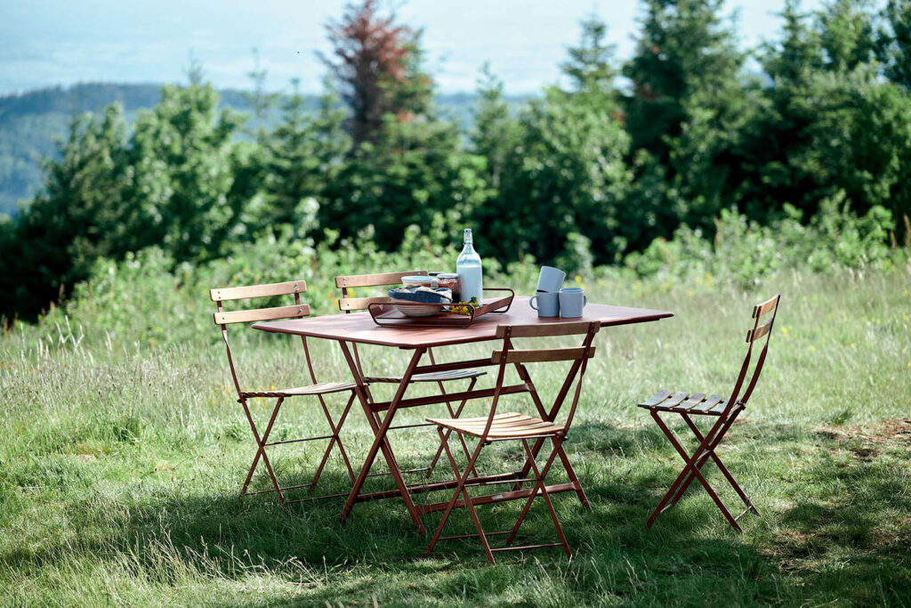 Une Chaise Bistro naturel installée à flanc de colline herbeuse, en pleine nature.