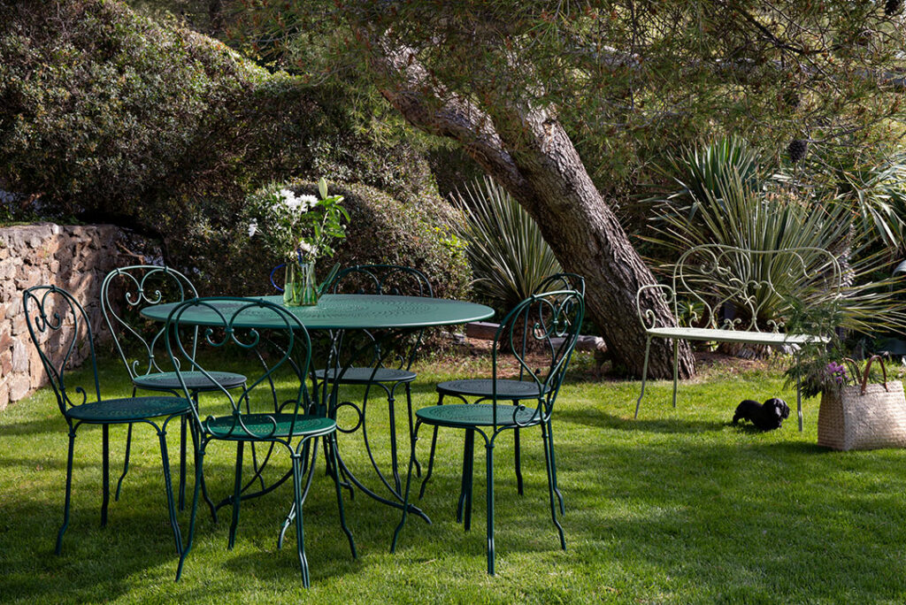 Une chaise verte 1900 et des chaises dans un jardin.