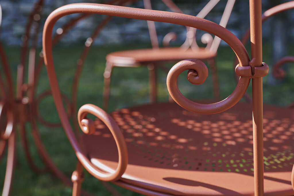 Un gros plan d'une chaise Fauteuil 1900 vintage en fer forgé orange.