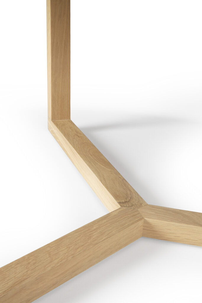 Gros plan de la Table basse Tripod en chêne présentant un design à trois branches inspiré d'un trépied sur une surface blanche.