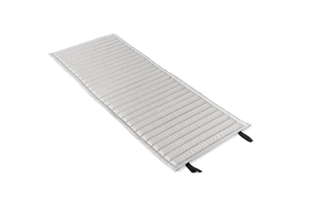 Un tapis de couchage matelassé blanc sur fond blanc.