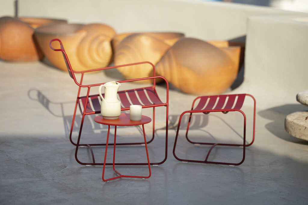 Une chaise en métal rouge et une Table d'appoint Cocotte sur une terrasse en béton.