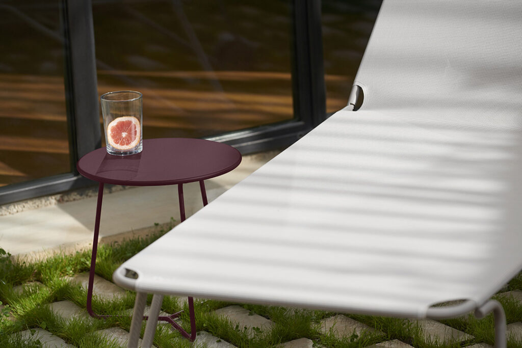 Une chaise longue blanche à côté d'un verre d'eau sur une Table d'appoint Cocotte.