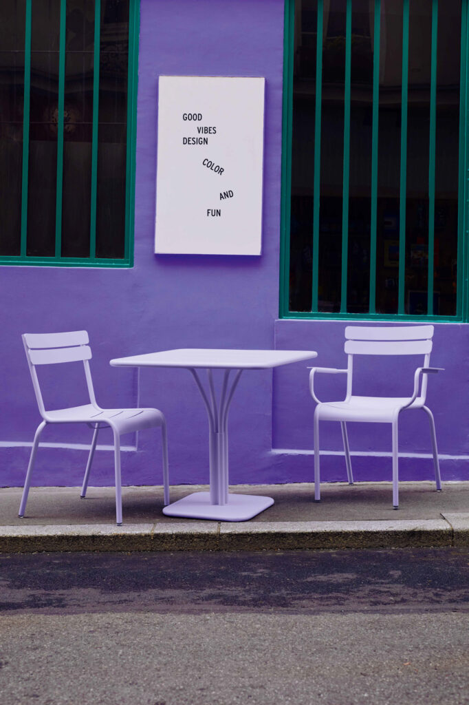 Deux chaises Fauteuil Luxembourg et une table Fauteuil Luxembourg devant un bâtiment violet.