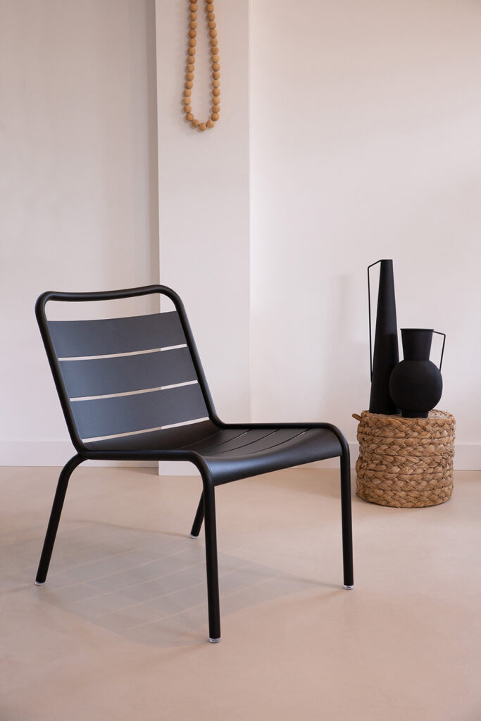 Une Chaise Lounge Luxembourg noire dans une pièce avec un vase.