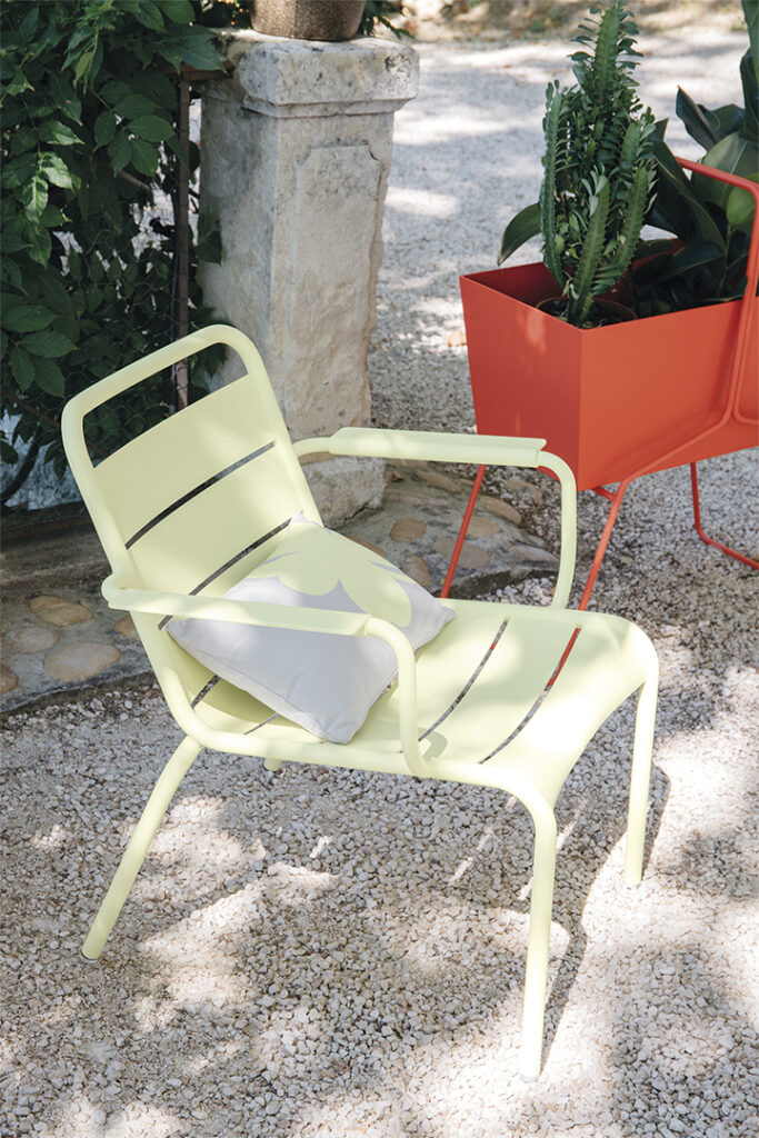Une chaise Fauteuil lounge Luxembourg jaune avec une plante en pot.