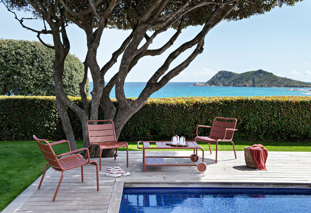 Un Fauteuil lounge Luxembourg et des transats au bord d'une piscine avec vue sur l'océan.