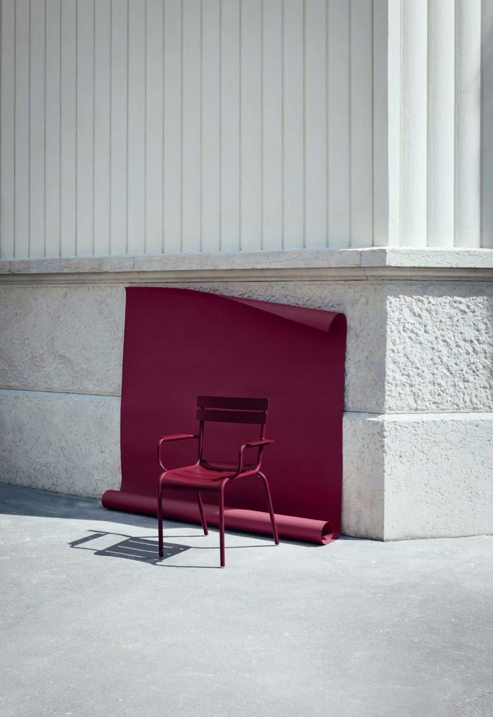 Une chaise Fauteuil Luxembourg rouge appuyée contre un mur.