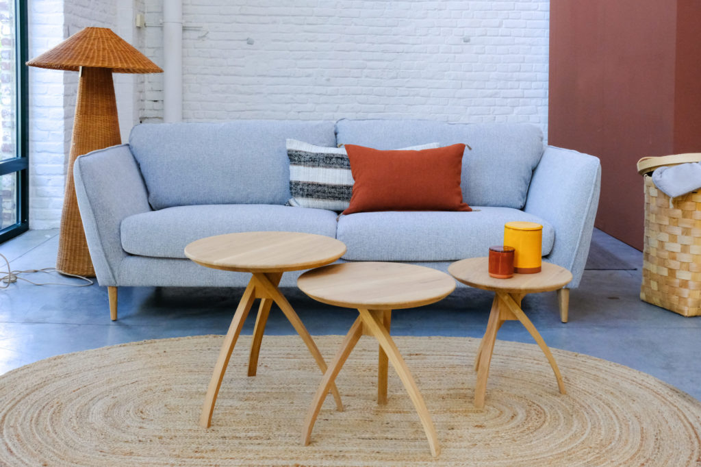 Canapé Stella de Sits avec trois tables basses rondes en chêne devant dans l'espace salon du showroom de Quatuor.