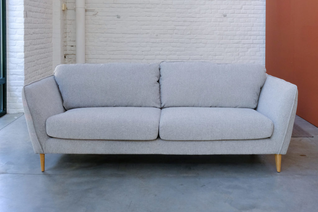 Un Canapé Stella gris devant un mur de briques.