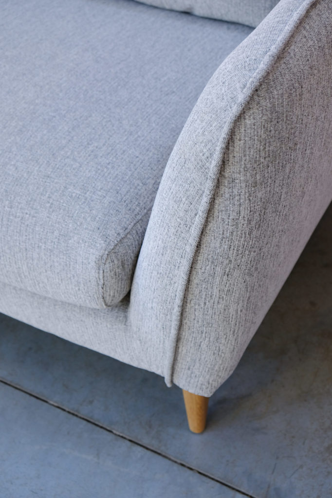 Un gros plan d'un Canapé Stella avec des pieds en bois.