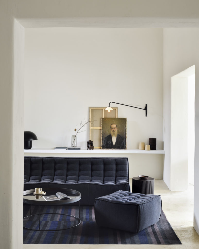 Un séjour avec un canapé noir et Repose-pieds N701.