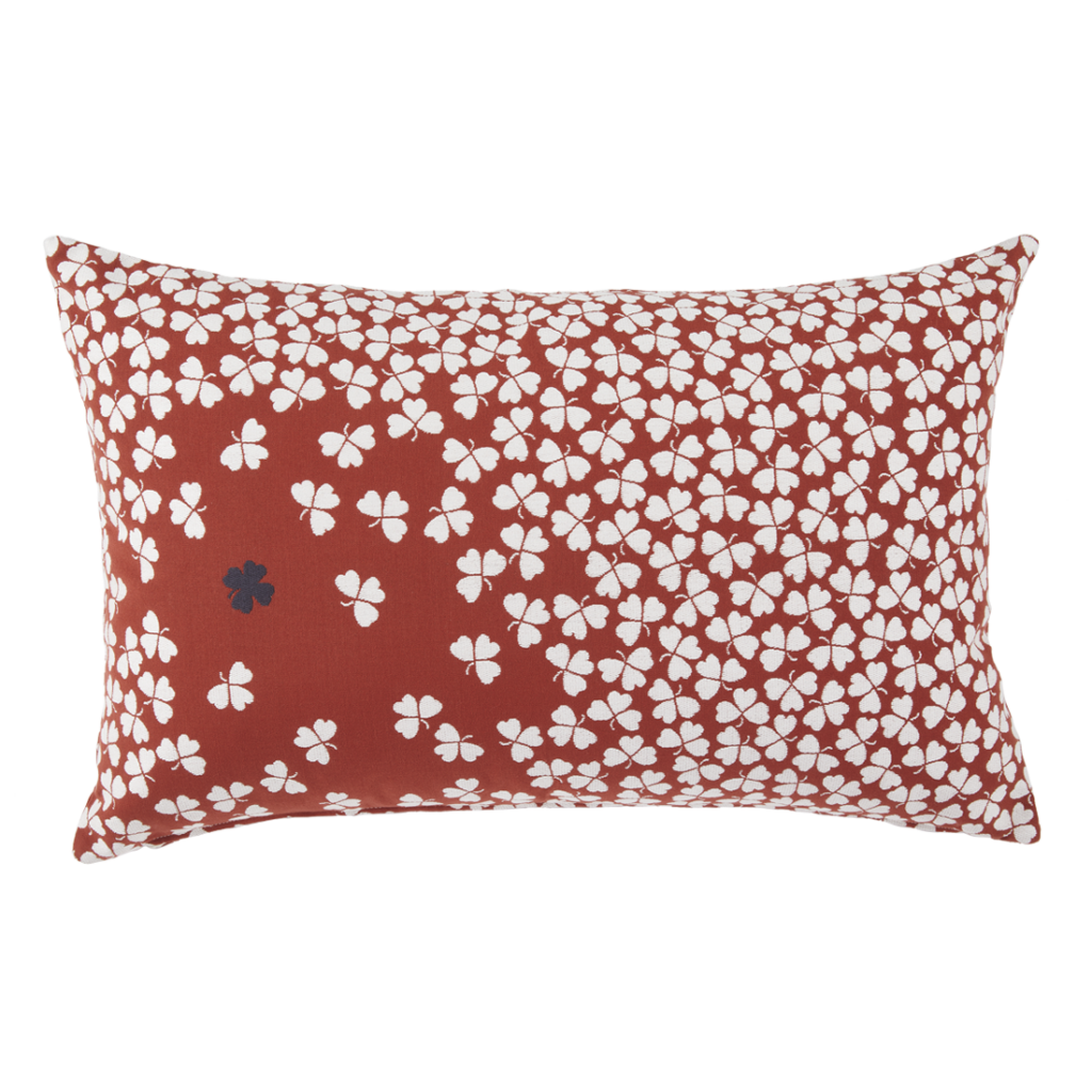 Un coussin rouge et blanc avec des fleurs blanches dessus.